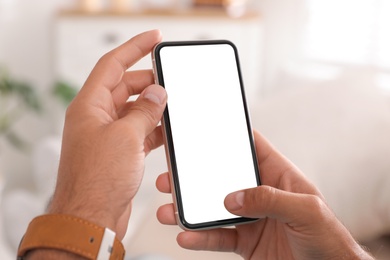 Man using mobile phone with empty screen indoors, closeup