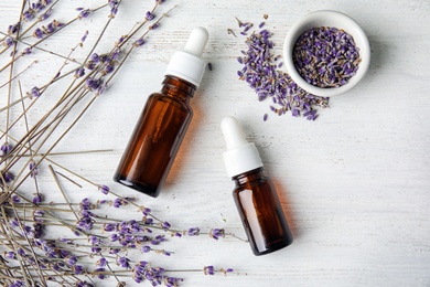 Flat lay composition with natural herbal oil and lavender flowers on wooden background