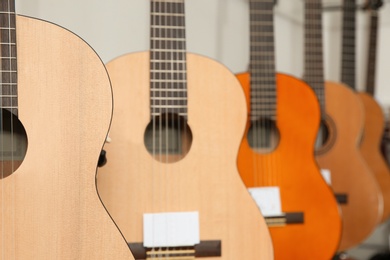 Photo of Modern wooden guitars in music store, closeup