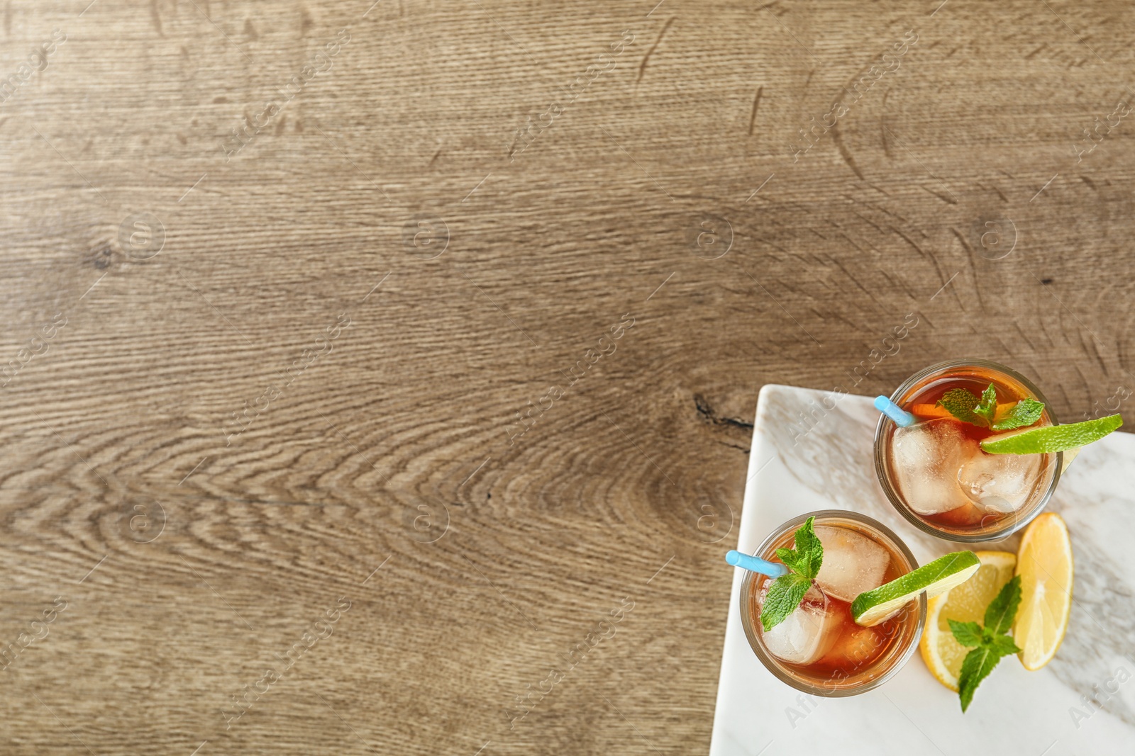 Photo of Glasses of refreshing iced tea on wooden table, top view. Space for text