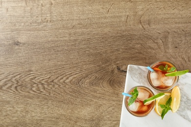 Glasses of refreshing iced tea on wooden table, top view. Space for text