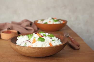 Bowl of boiled rice with vegetables on table. Space for text