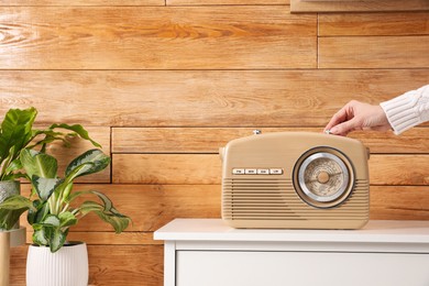 Photo of Woman turning volume knob on radio indoors, closeup. Space for text