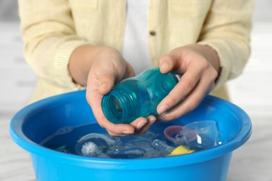 Photo of Woman washing baby bottle above basin, closeup