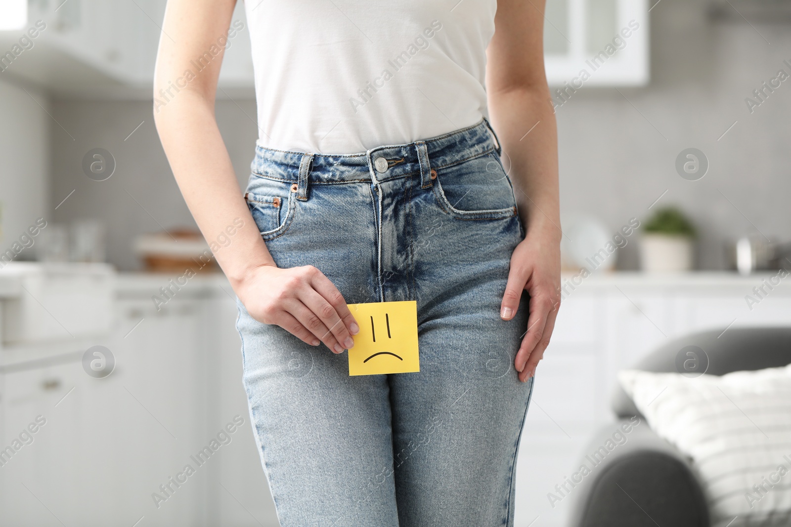 Photo of Cystitis. Woman holding sticky note with drawn sad face at home, closeup