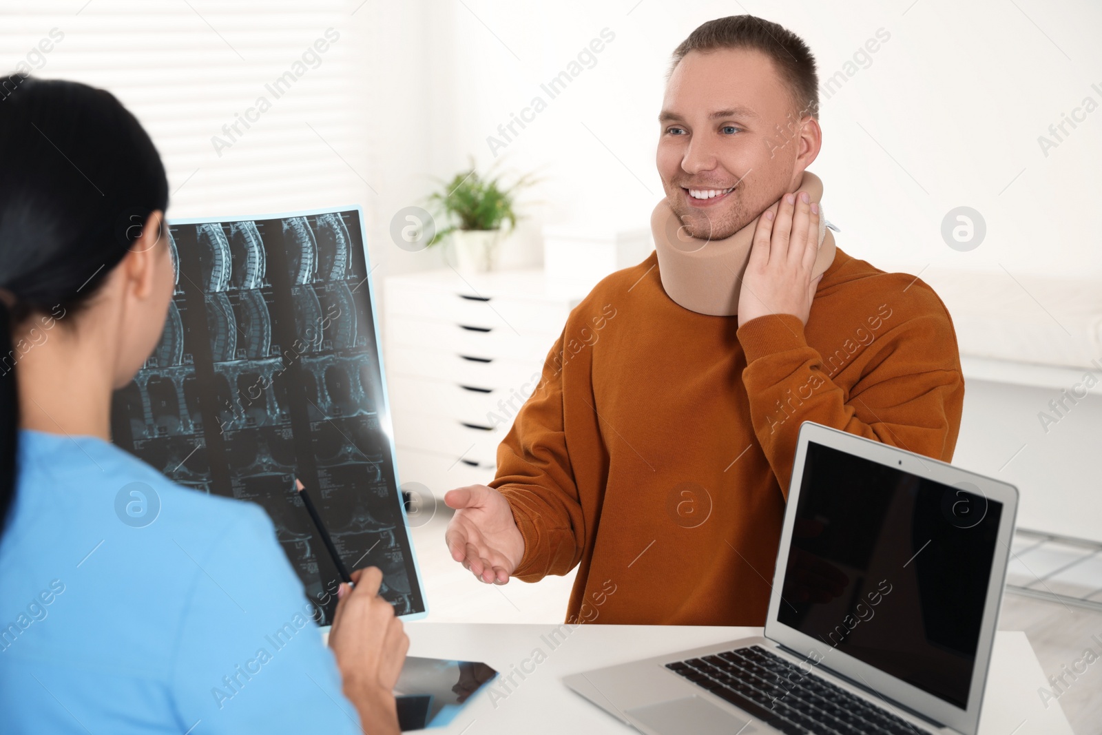 Photo of Doctor with neck MRI image consulting patient in clinic