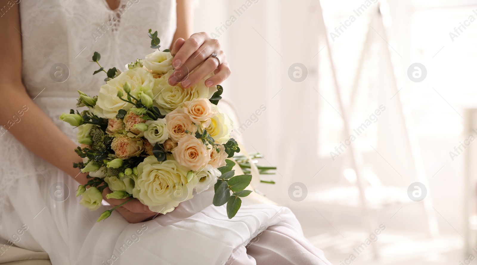 Photo of Young bride with beautiful wedding bouquet in room, closeup. Space for text