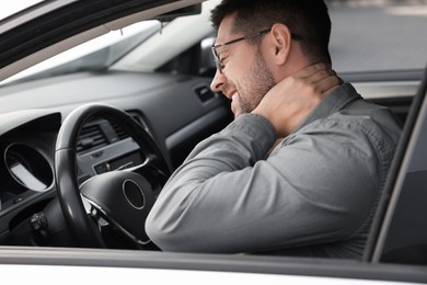 Man suffering from neck pain in car