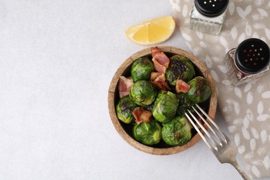 Photo of Delicious roasted Brussels sprouts and bacon served on light table, top view. Space for text