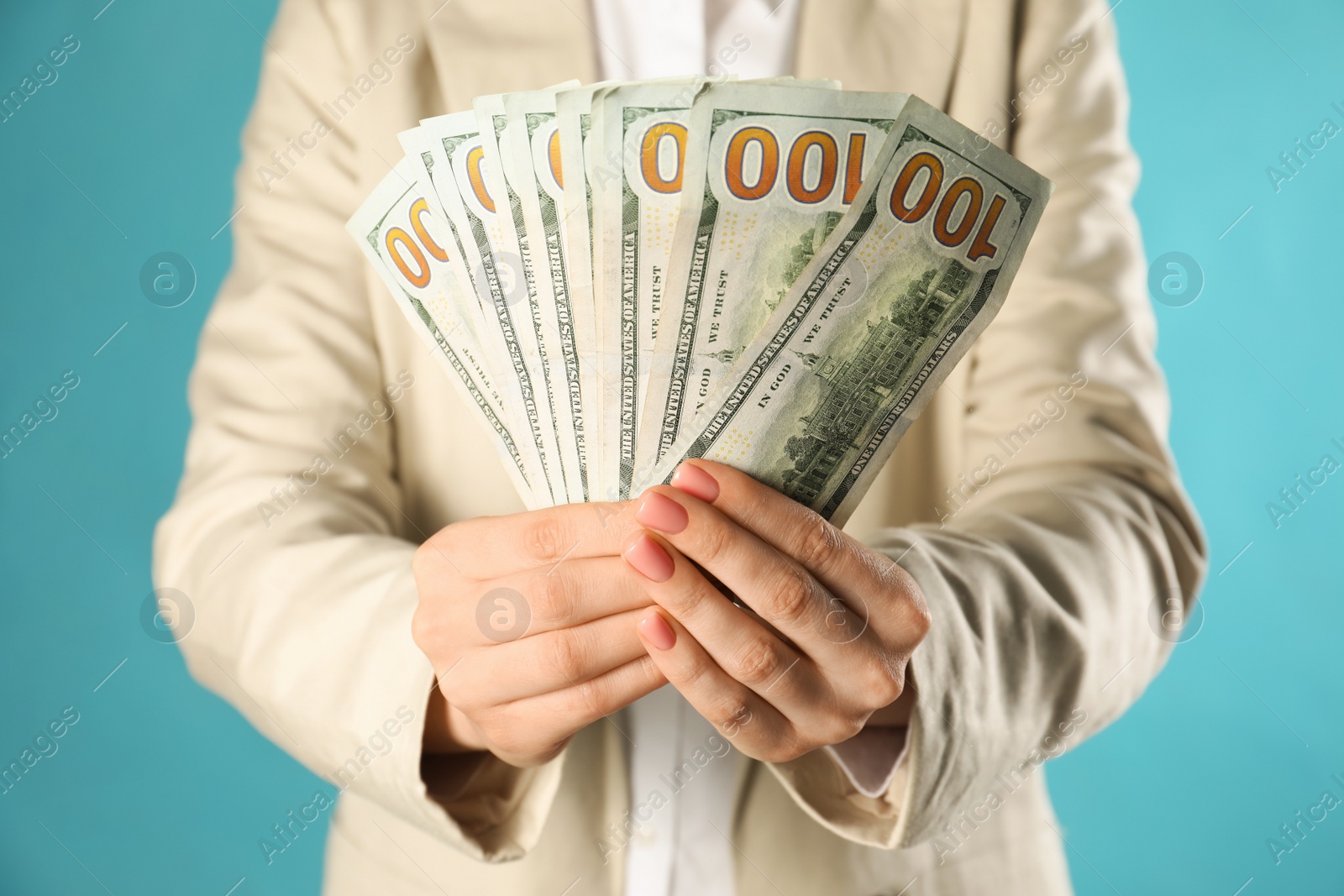 Photo of Woman holding dollar banknotes on turquoise background, closeup. Money exchange concept