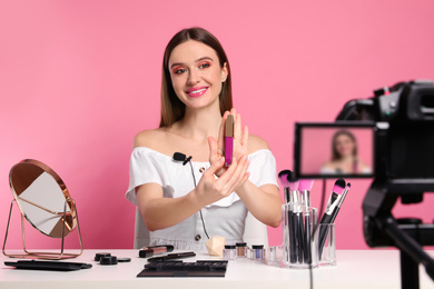 Beauty blogger recording makeup tutorial on pink background