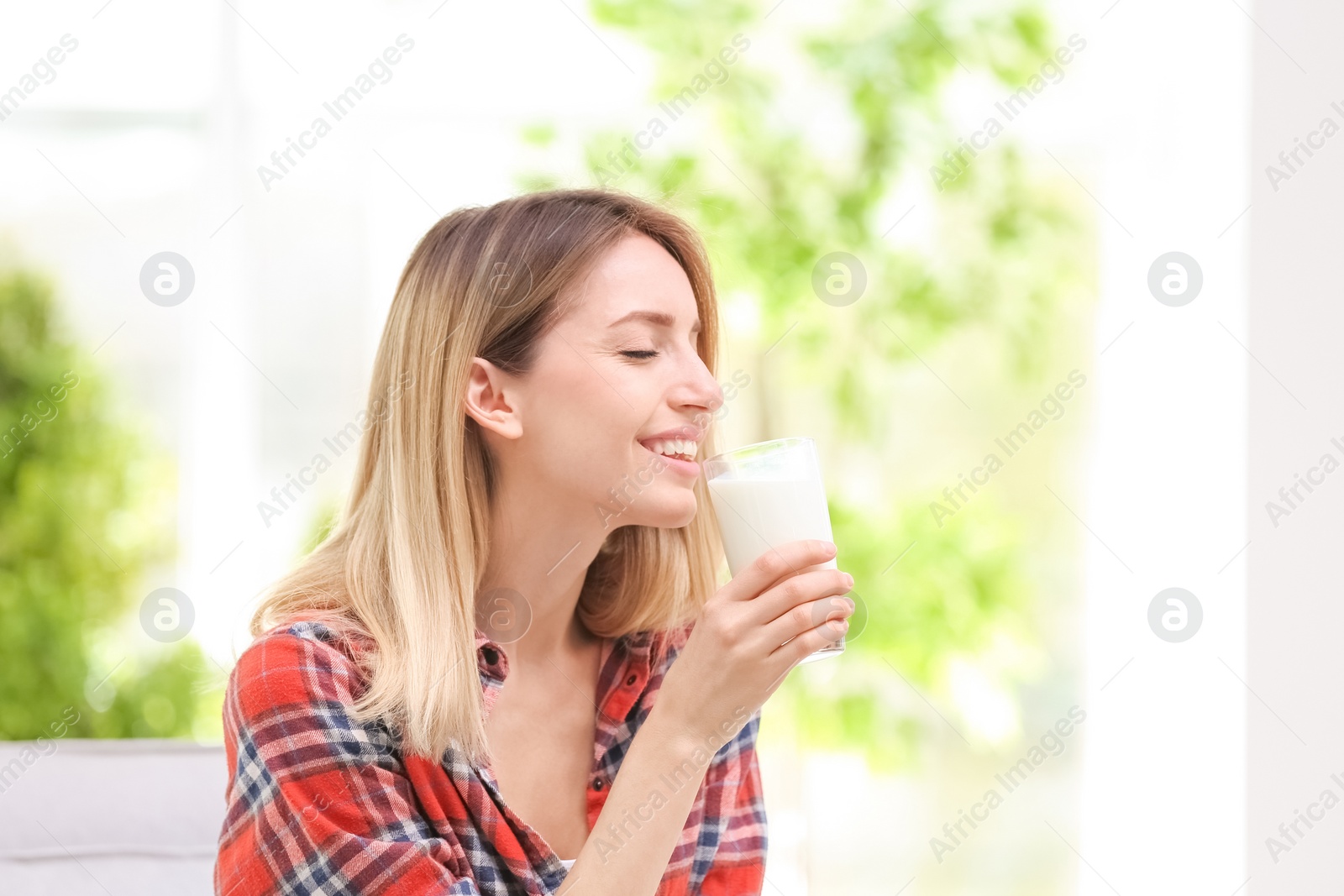 Photo of Beautiful young woman drinking milk at home