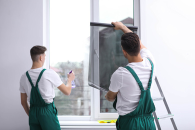 Professional workers tinting window with foil indoors