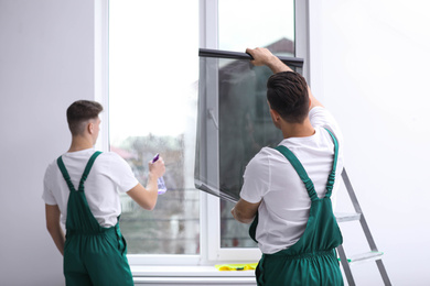 Photo of Professional workers tinting window with foil indoors