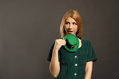 Photo of Young woman with green leprechaun hat on grey background, space for text. St. Patrick's Day celebration