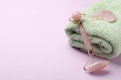 Photo of Natural face roller, towel and gua sha tool on pink background. Space for text