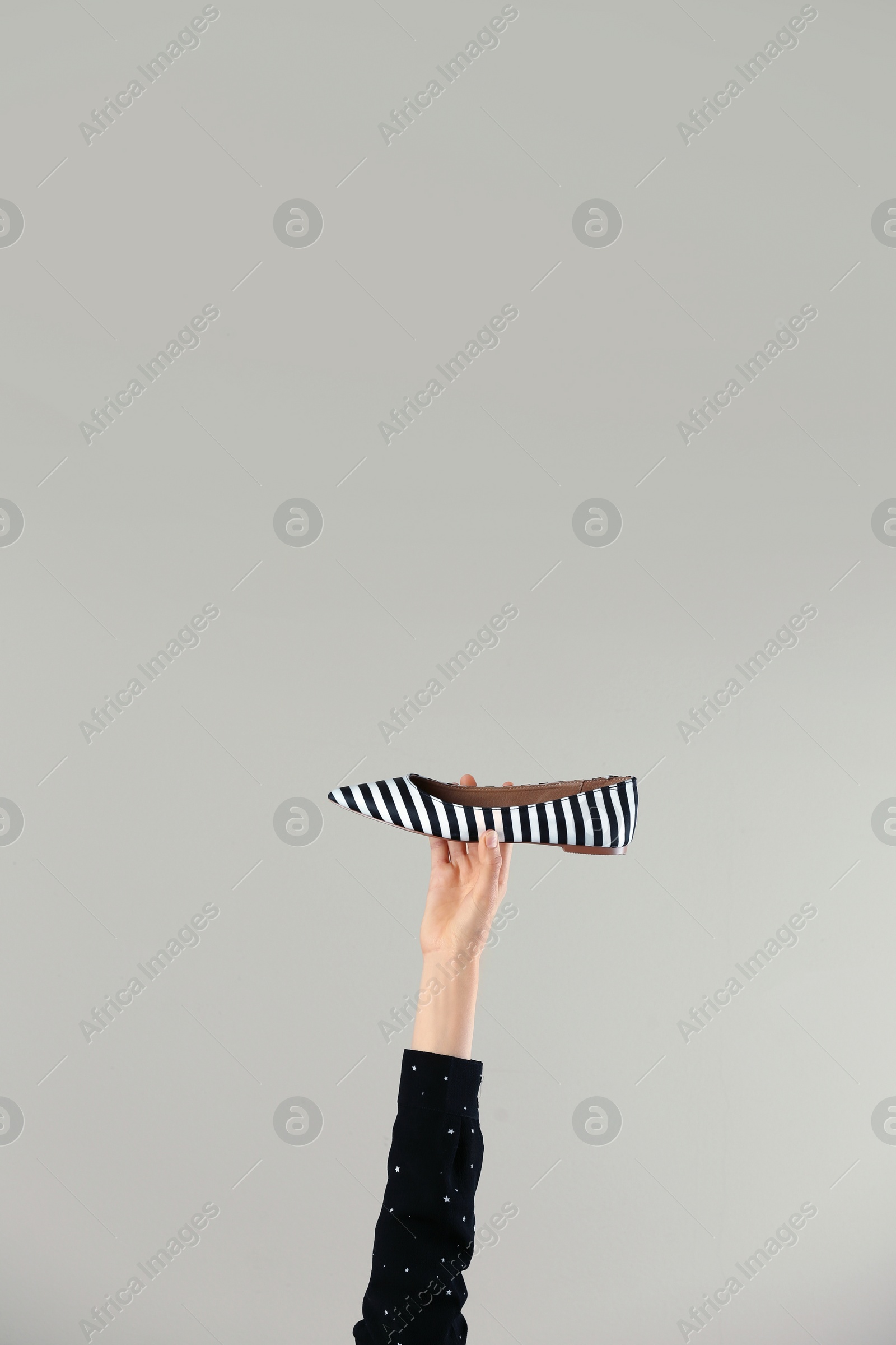 Photo of Woman holding stylish shoe on light background, closeup. Space for text