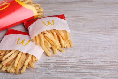 MYKOLAIV, UKRAINE - AUGUST 12, 2021: Small and big portions of McDonald's French fries on white wooden table, space for text