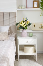 Photo of Bouquet of beautiful flowers on nightstand in bedroom