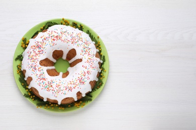 Photo of Glazed Easter cake with sprinkles on white wooden table, top view. Space for text