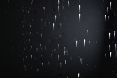 Photo of Water drops falling on black background. Rainy weather