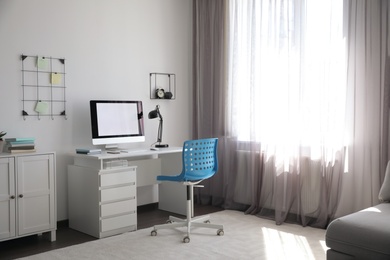 Comfortable blue chair near desk in stylish office interior