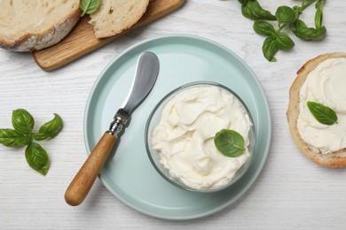 Photo of Tasty cream cheese with basil and fresh bread on white wooden table, flat lay