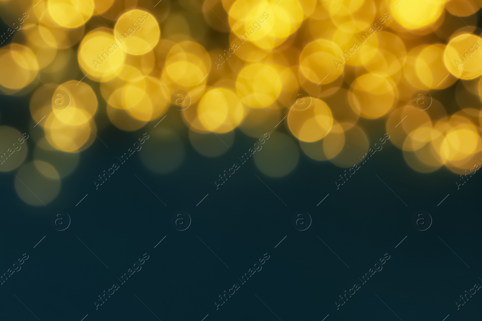 Photo of Blurred view of glowing Christmas lights on blue background. Space for text