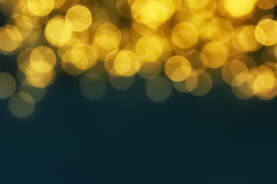 Blurred view of glowing Christmas lights on blue background. Space for text