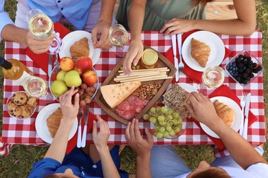 Young people having picnic at table in park, top view