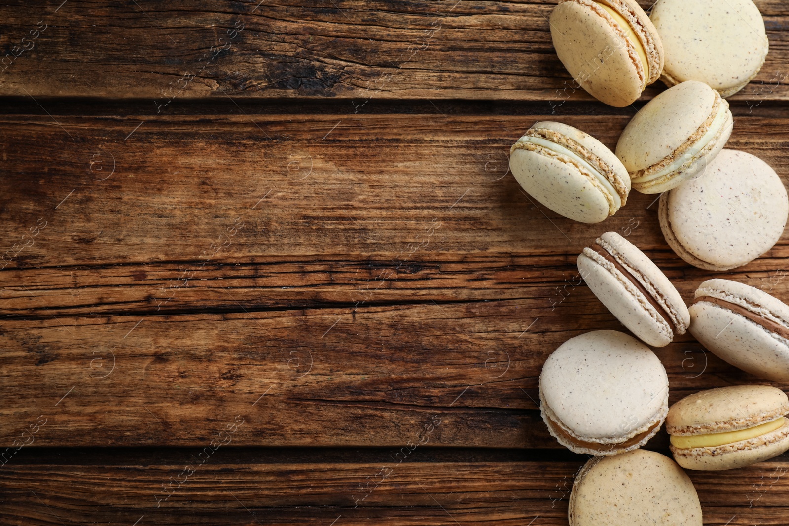 Photo of Delicious macarons on wooden table, flat lay. Space for text