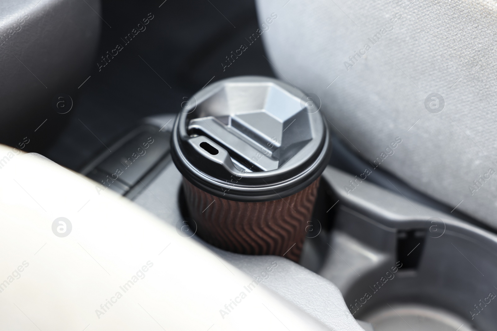 Photo of Coffee to go. Paper cup with tasty drink in holder inside of car, closeup