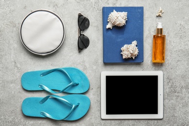 Flat lay composition with tablet and beach objects on light background