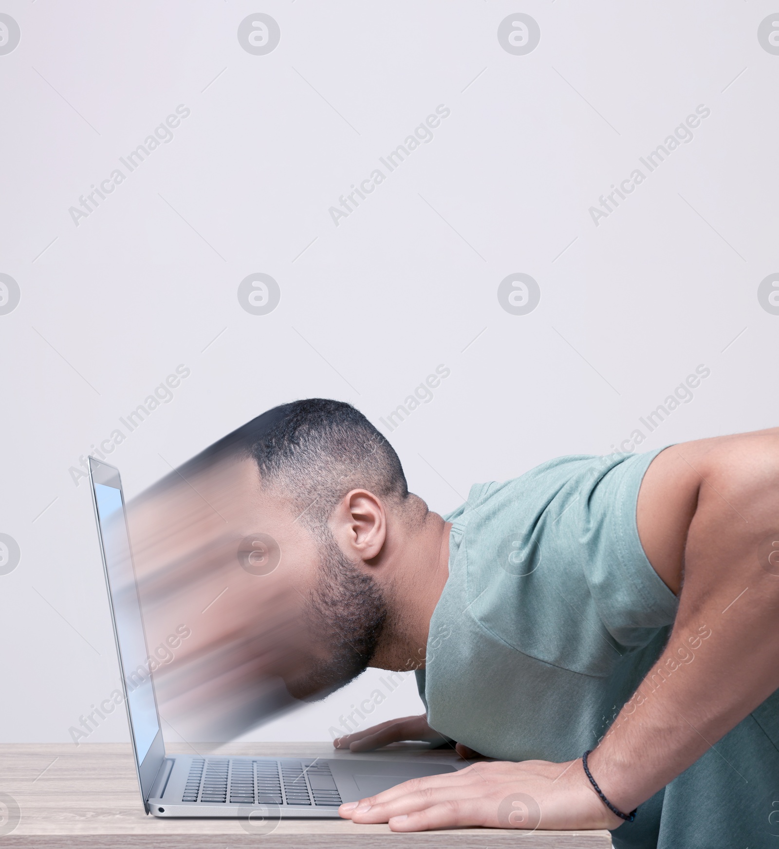 Image of Internet addiction. Young man dissolving in laptop at table