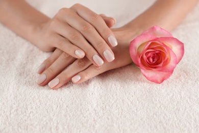 Woman with smooth hands and flower on towel, closeup. Spa treatment