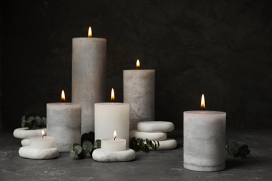 Photo of Composition with burning candles, spa stones and eucalyptus on grey table