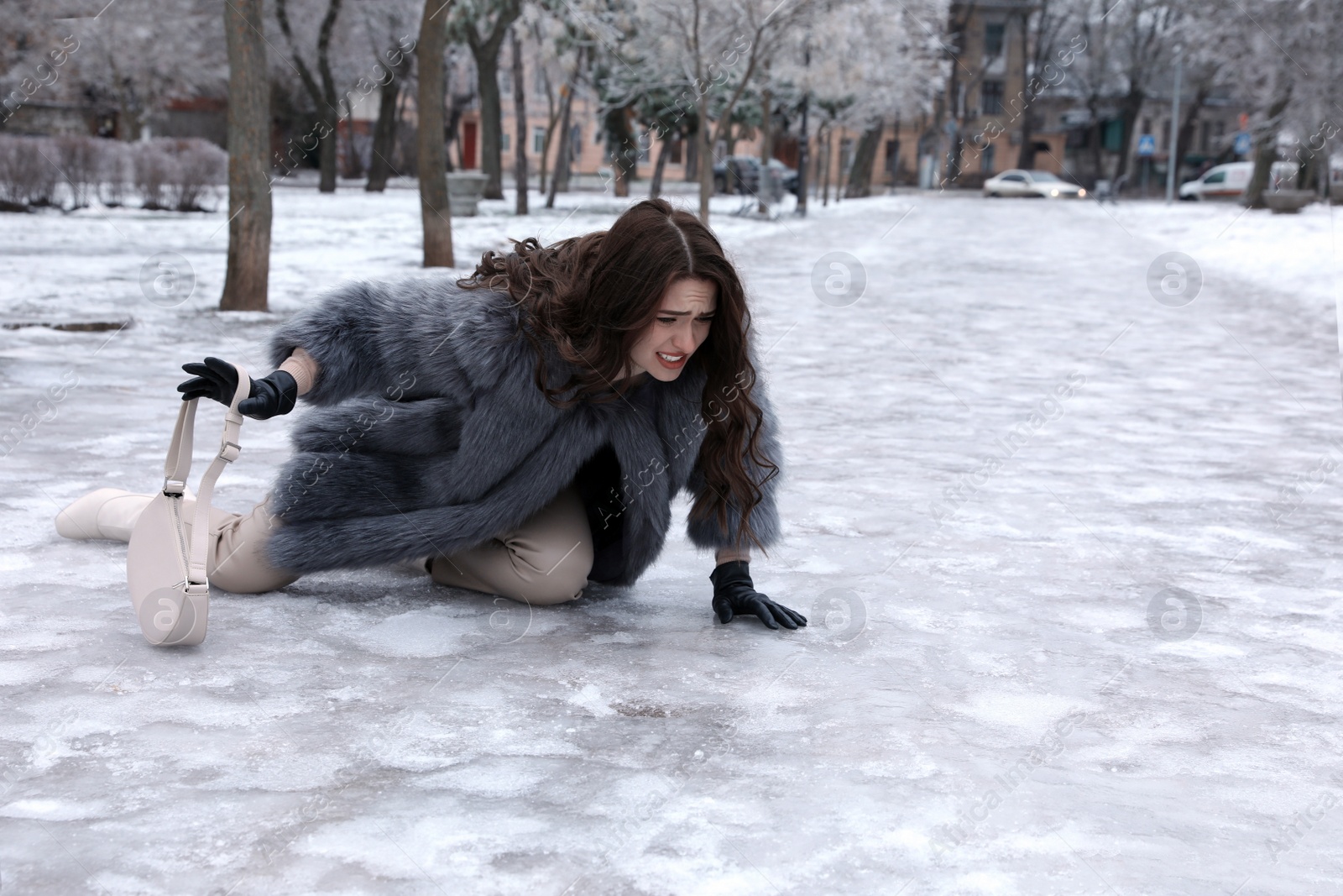 Photo of Young woman fallen on slippery icy pavement in park