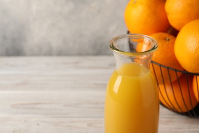 Photo of Tasty fresh oranges and juice in jug on white wooden table, closeup. Space for text