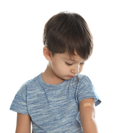 Photo of Little boy with sticking plaster on arm against white background