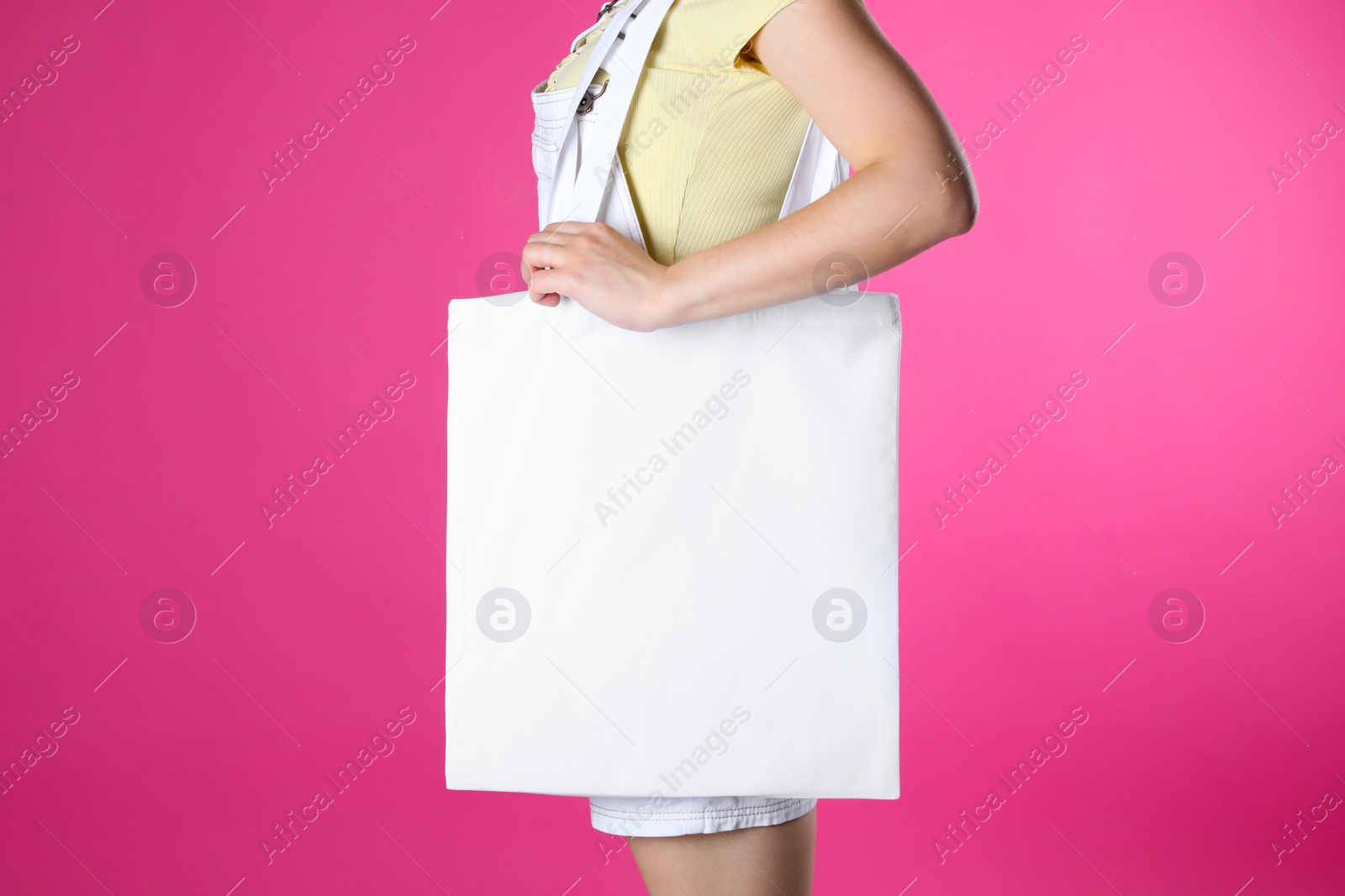 Photo of Woman with white textile bag on pink background, closeup. Space for design