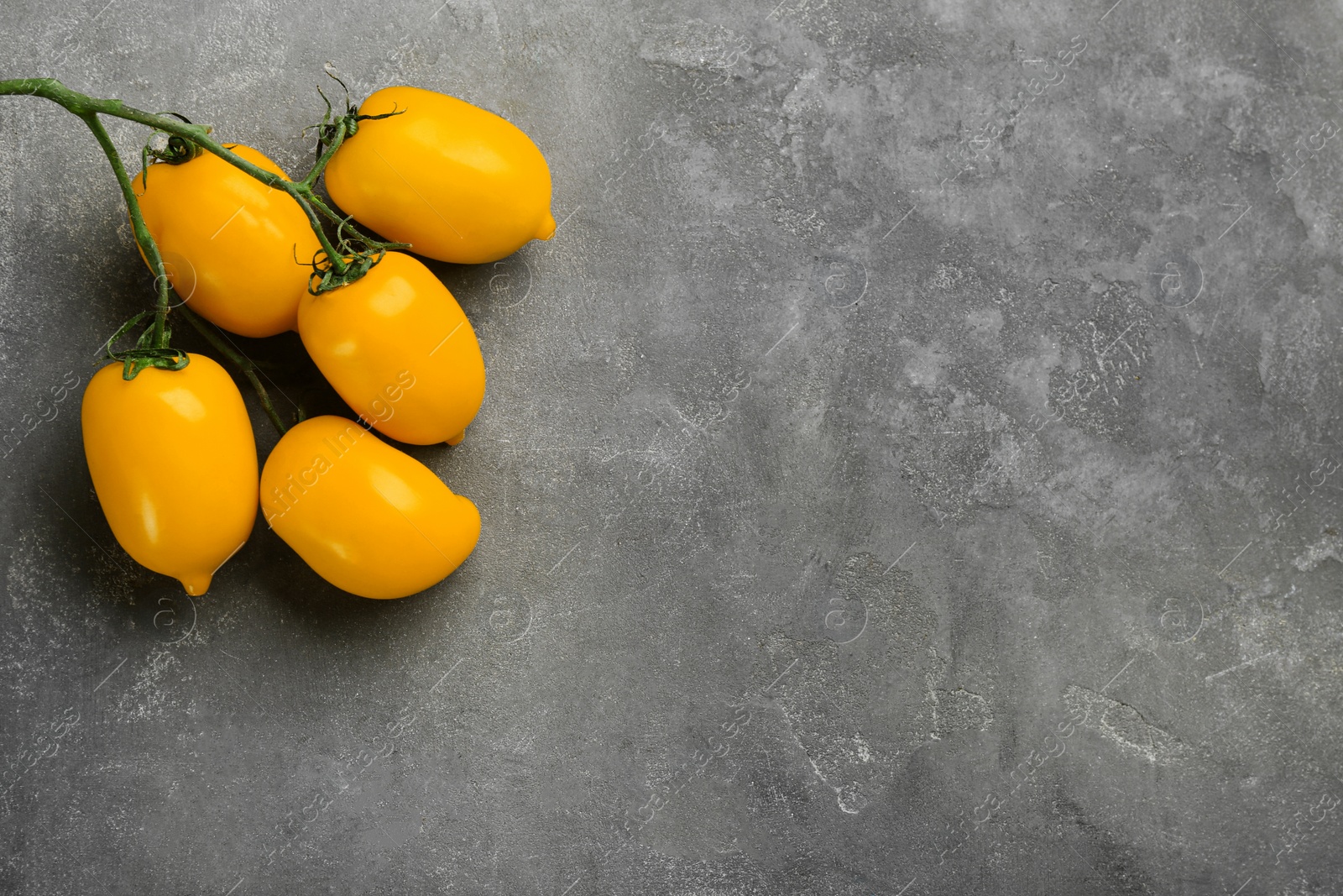 Photo of Ripe yellow tomatoes on grey table, flat lay. Space for text