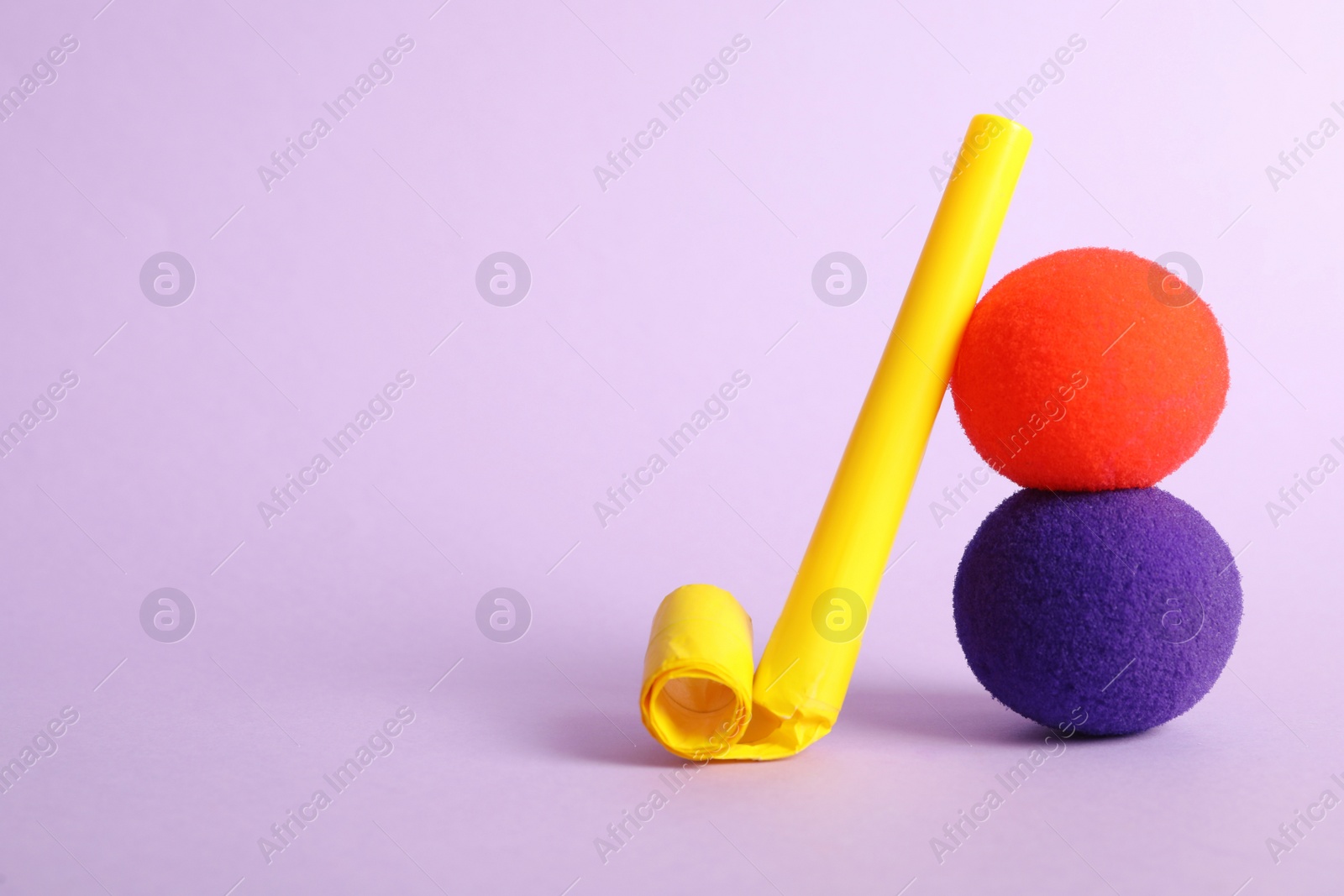 Photo of Clown noses and party blower on violet background, space for text