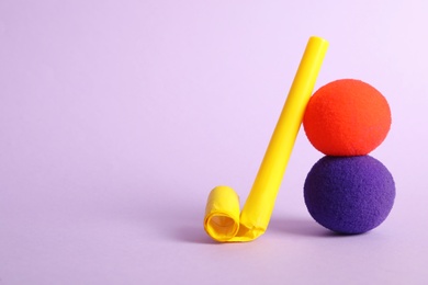 Photo of Clown noses and party blower on violet background, space for text