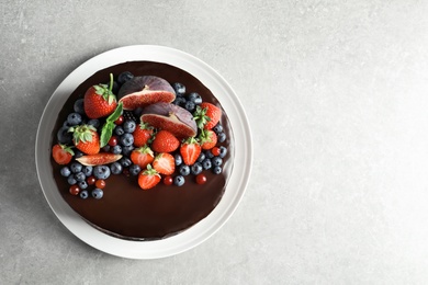 Fresh delicious homemade chocolate cake with berries on gray table, top view. Space for text