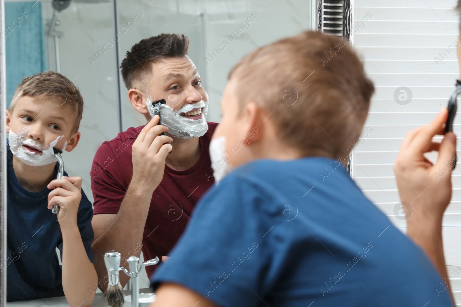 Photo of Dad shaving and son imitating him at mirror in bathroom