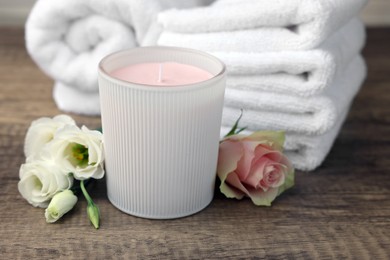 Photo of Scented candle, folded towels and flowers on wooden table