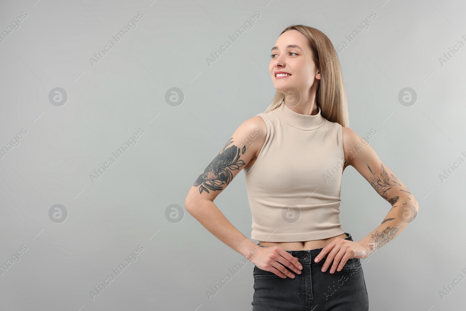 Photo of Portrait of beautiful tattooed woman on gray background, space for text