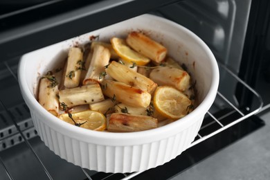 Dish with baked salsify roots, lemon and thyme in oven