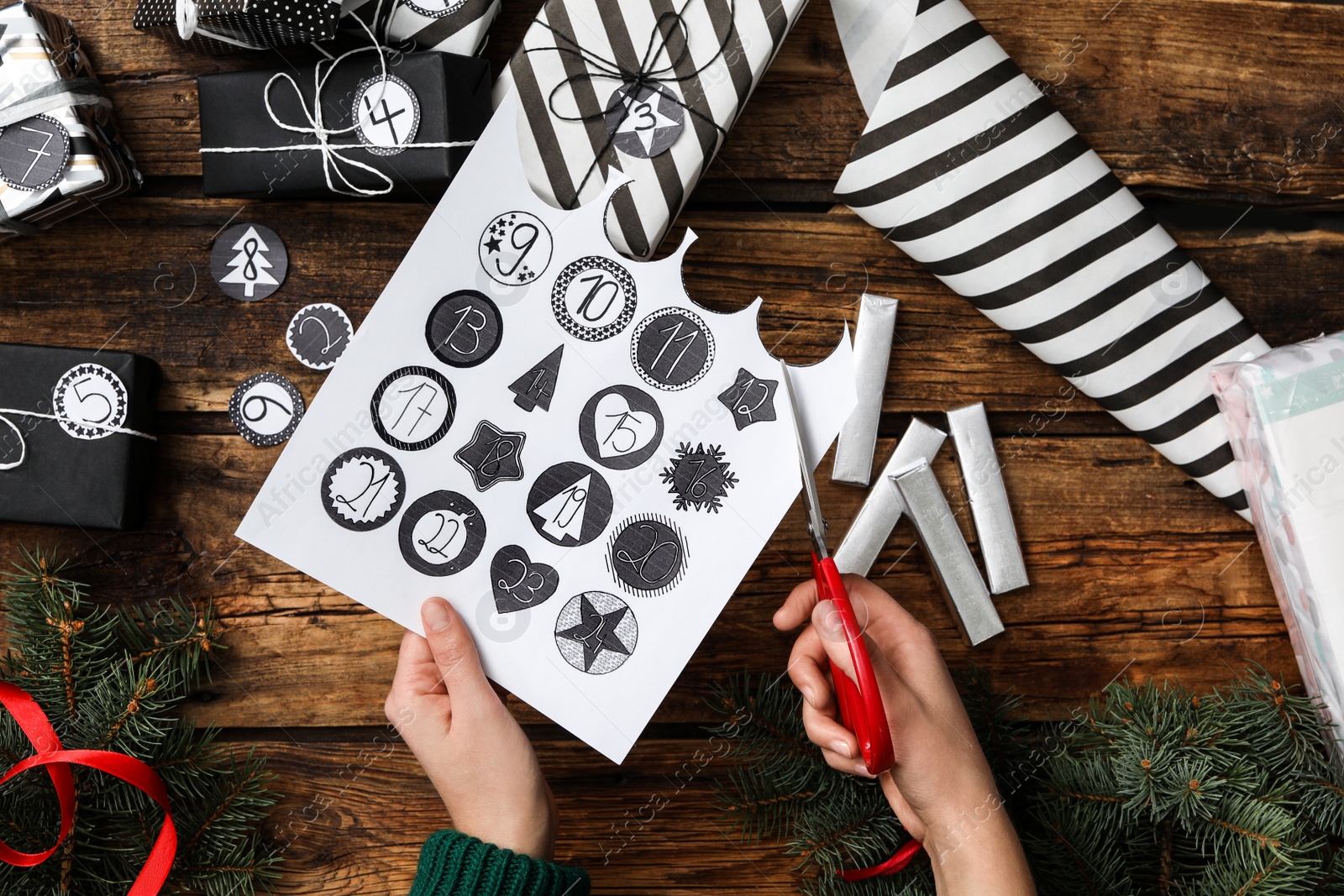 Photo of Woman making advent calendar at wooden table, top view