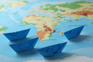 Light blue paper boats on world map